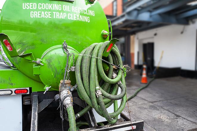 worker pumping grease trap at commercial kitchen in Ainsworth, IA